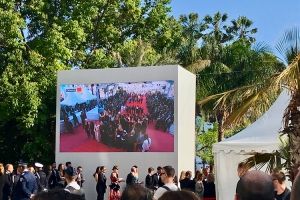 Big screen showing red carpet with people gathered on it